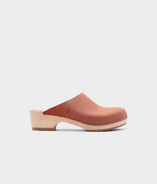low heeled minimalistic clog mules in blush pink nubuck leather stapled on a light wooden base