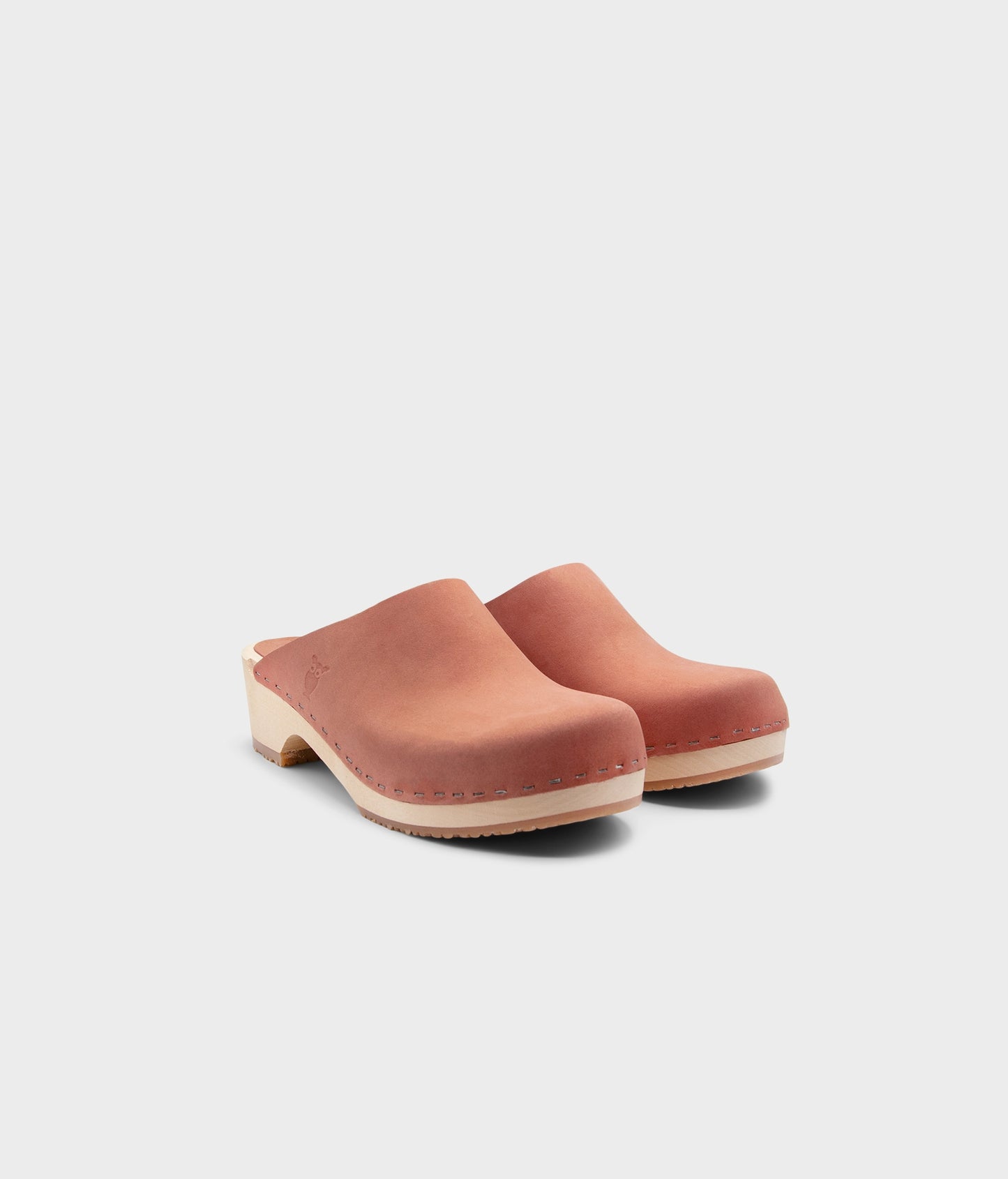 low heeled minimalistic clog mules in blush pink nubuck leather stapled on a light wooden base