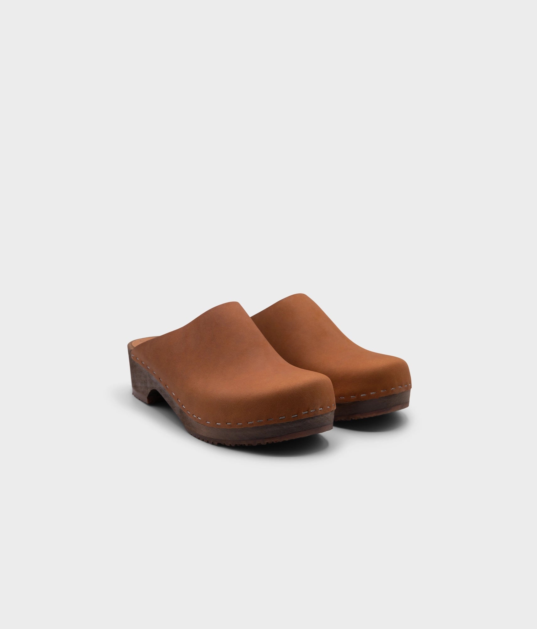 low heeled minimalistic clog mules in dexter tan nubuck leather stapled on a dark wooden base