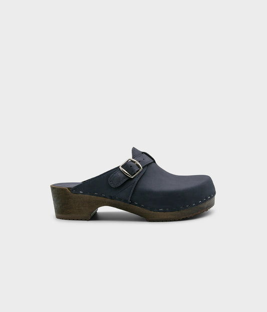 men's clog mule in navy blue nubuck leather stapled on a dark wooden base with a silver buckle on top