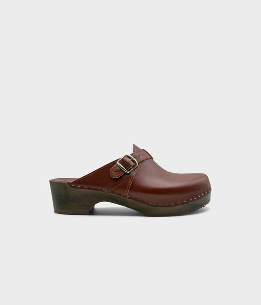 men's clog mule in cognac red vegetable tanned leather stapled on a dark wooden base with a silver buckle on top