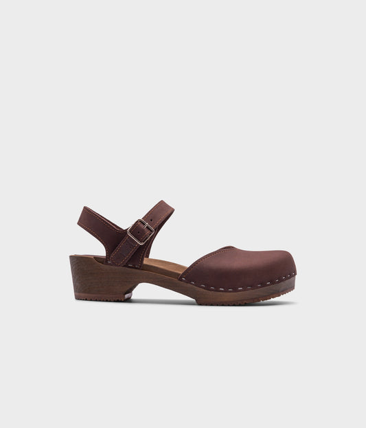 classic low heeled closed-toe sandal in dark brown nubuck leather stapled on a dark wooden base