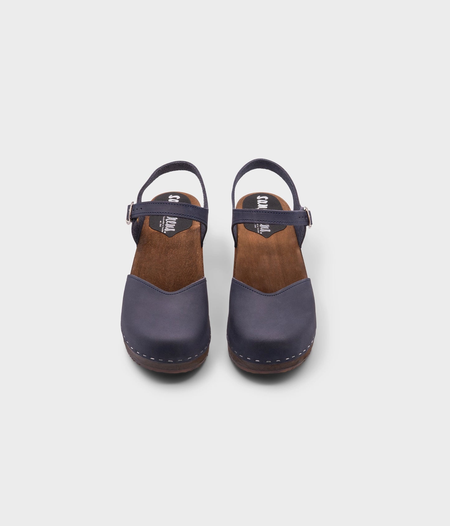 classic low heeled closed-toe sandal in navy blue nubuck leather stapled on a dark wooden base