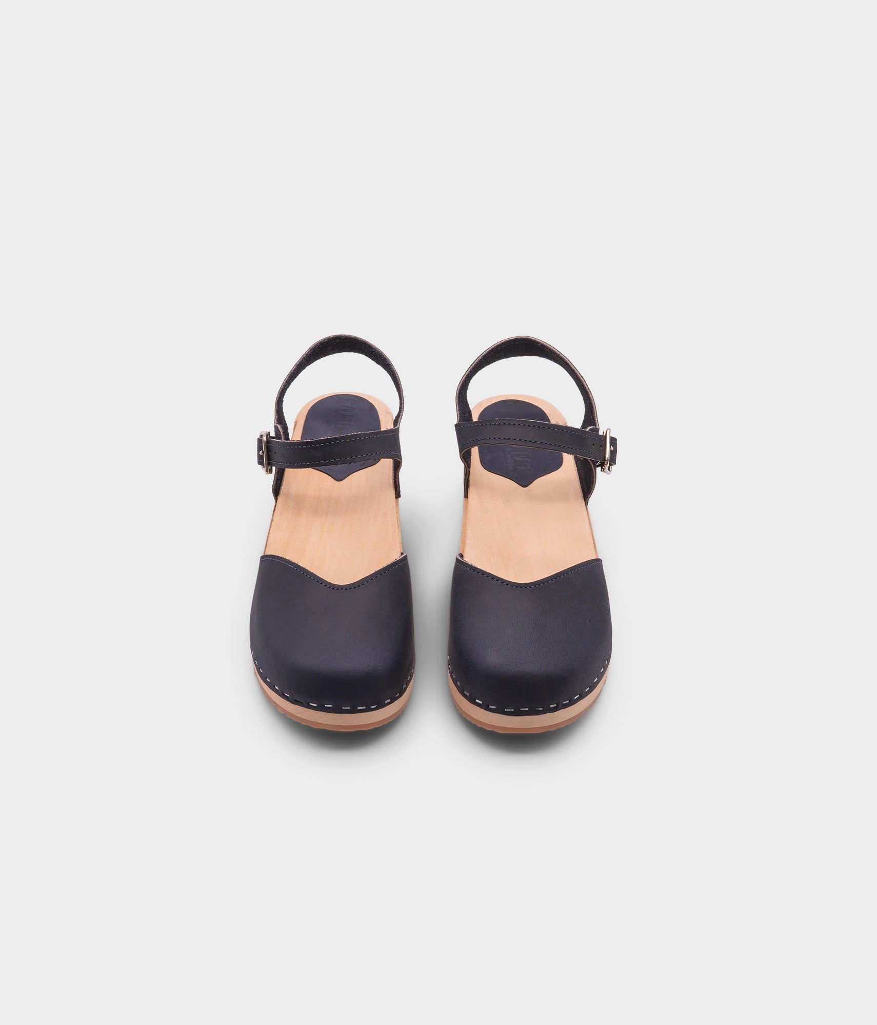 classic low heeled closed-toe sandal in navy blue nubuck leather stapled on a light wooden base