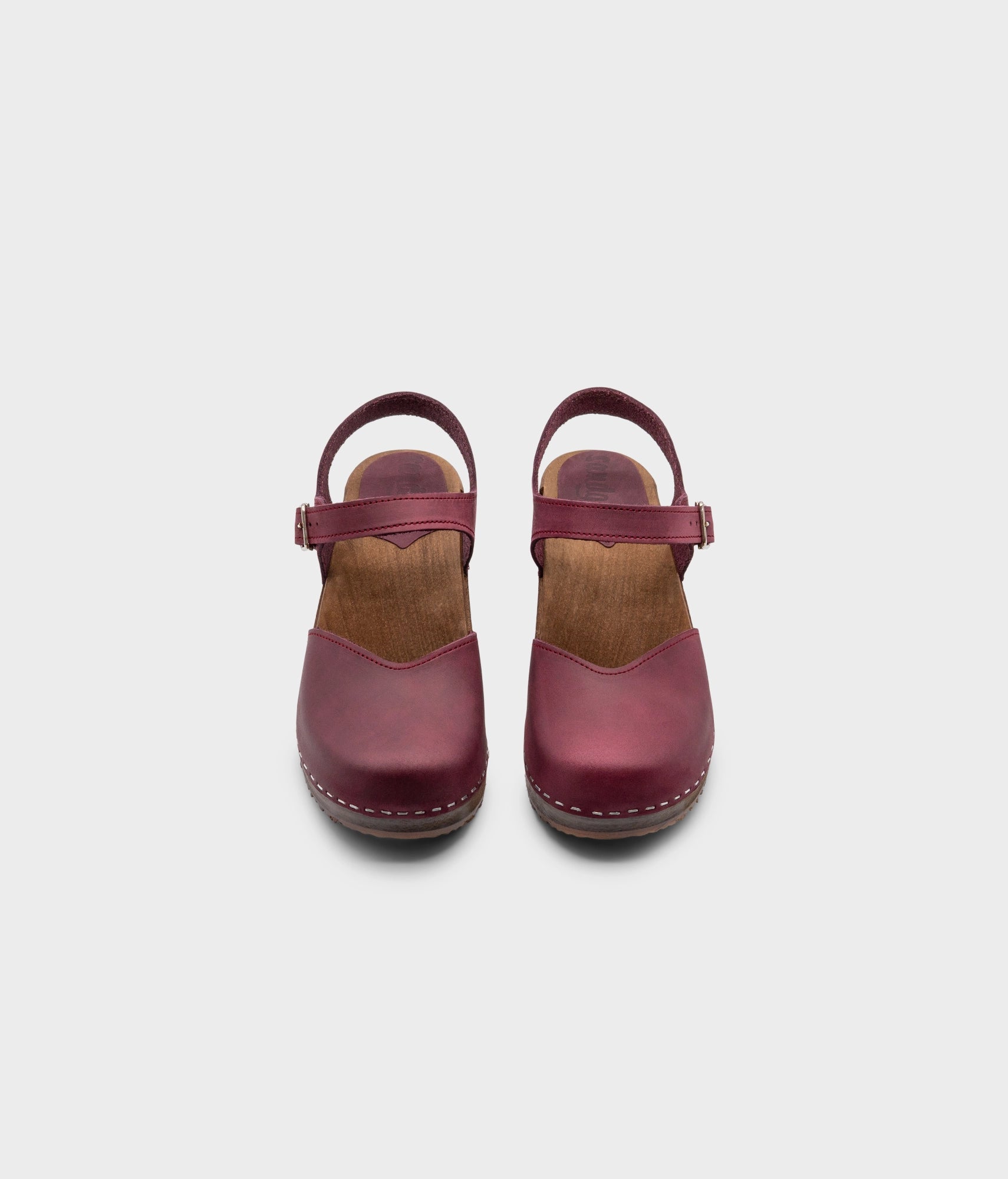 classic low heeled closed-toe sandal in purple plum nubuck leather stapled on a dark wooden base