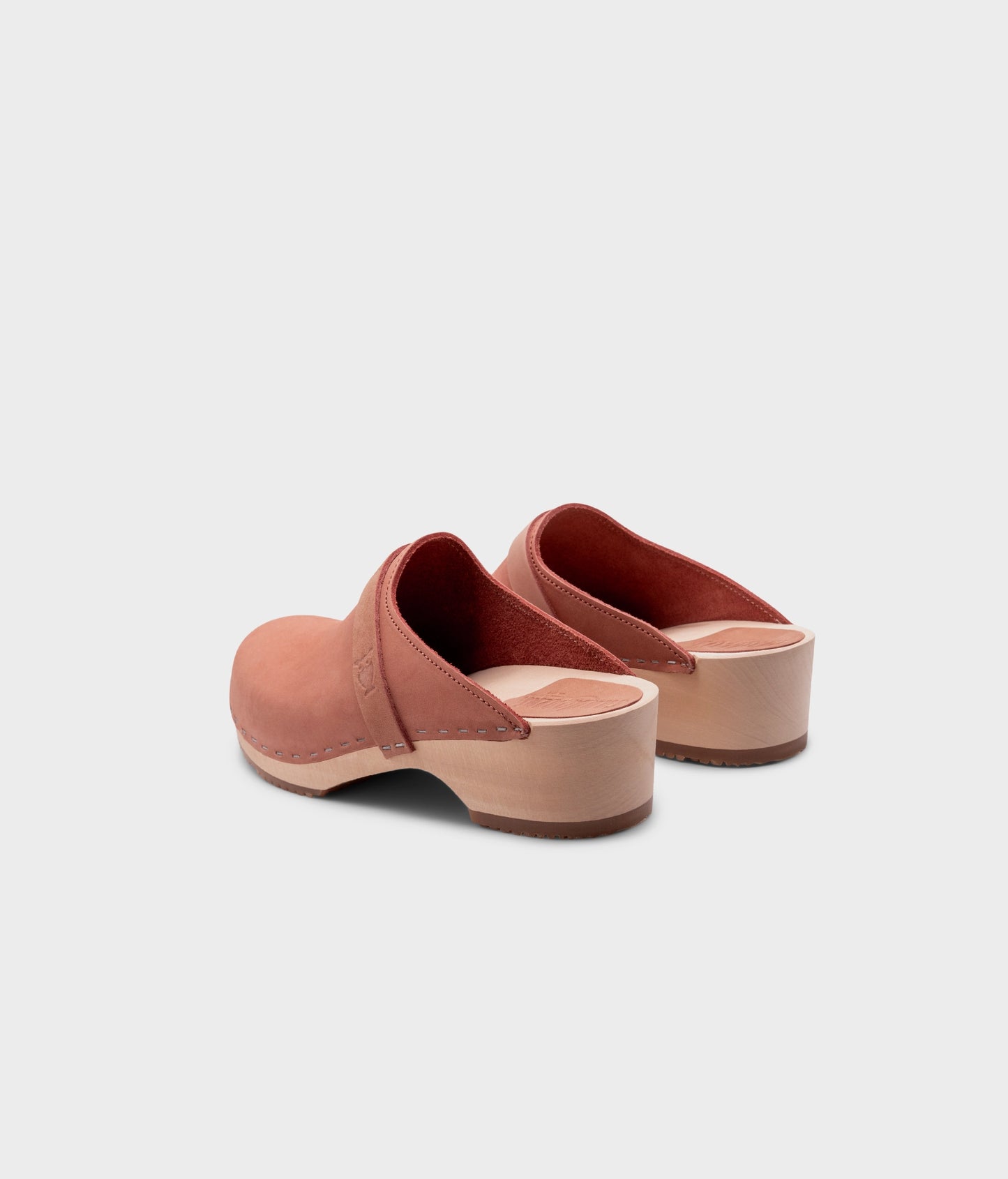 classic low heeled clog mule in blush pink nubuck leather stapled on a light wooden base with a leather strap