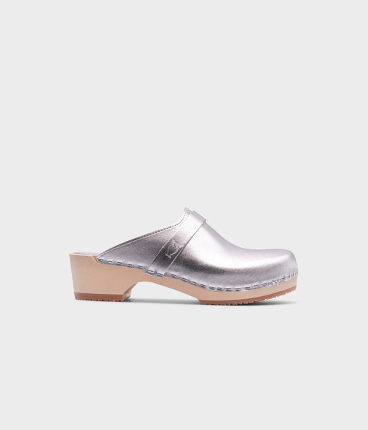 classic low heeled clog mule in metallic silver traditional leather stapled on a light wooden base with a leather strap