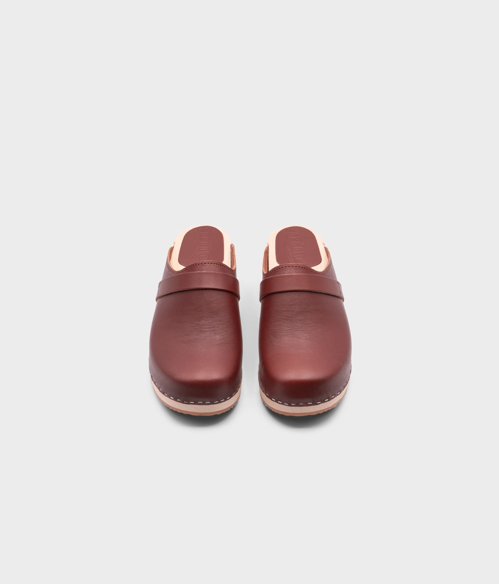 classic low heeled clog mule in cognac red vegetable tanned leather stapled on a light wooden base with a leather strap