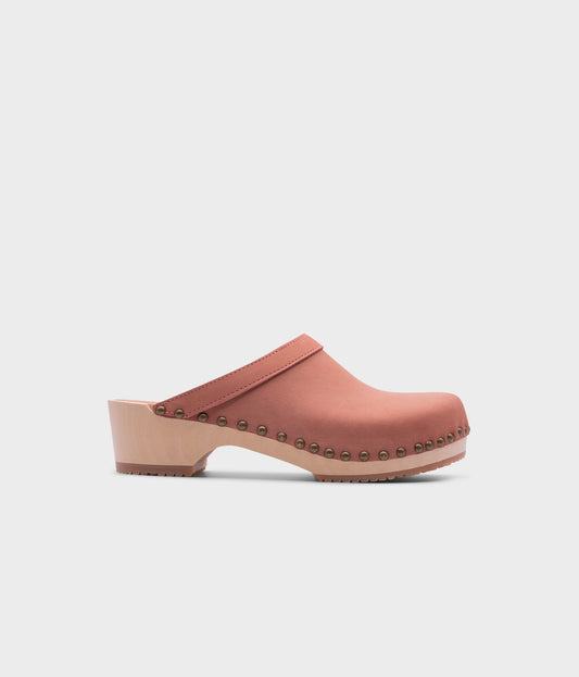 low heeled clog mules in blush pink nubuck leather stapled on a light wooden base with brass gold studs