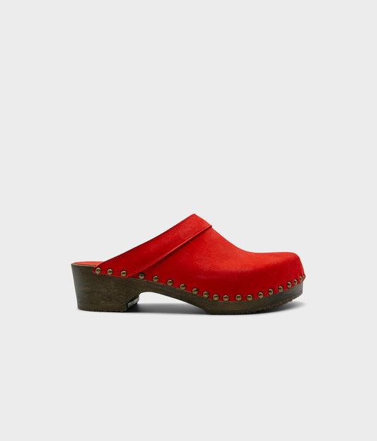 low heeled clog mules in red nubuck leather stapled on a dark wooden base with brass gold studs