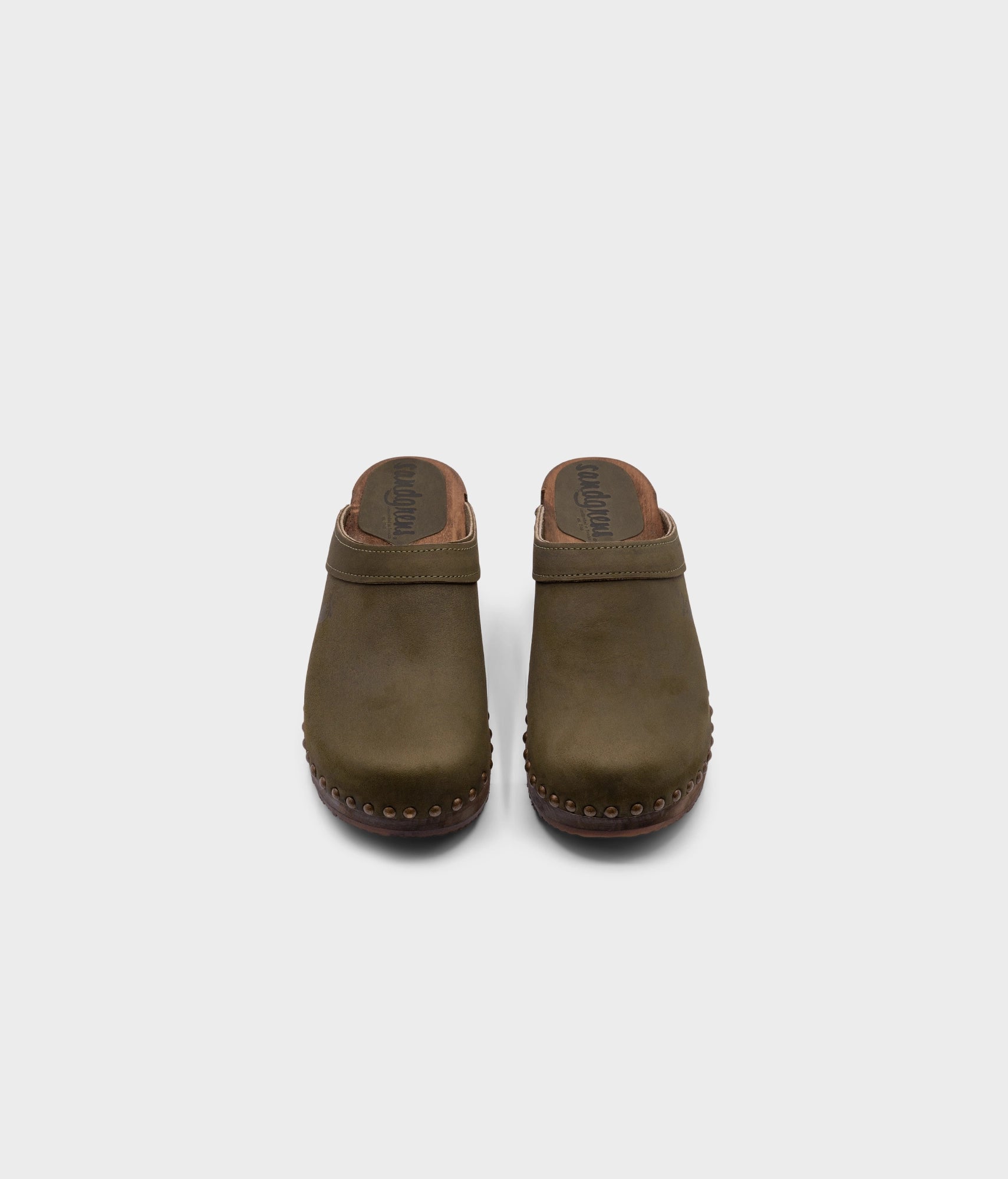 low heeled clog mules in olive nubuck leather stapled on a dark wooden base with brass gold studs