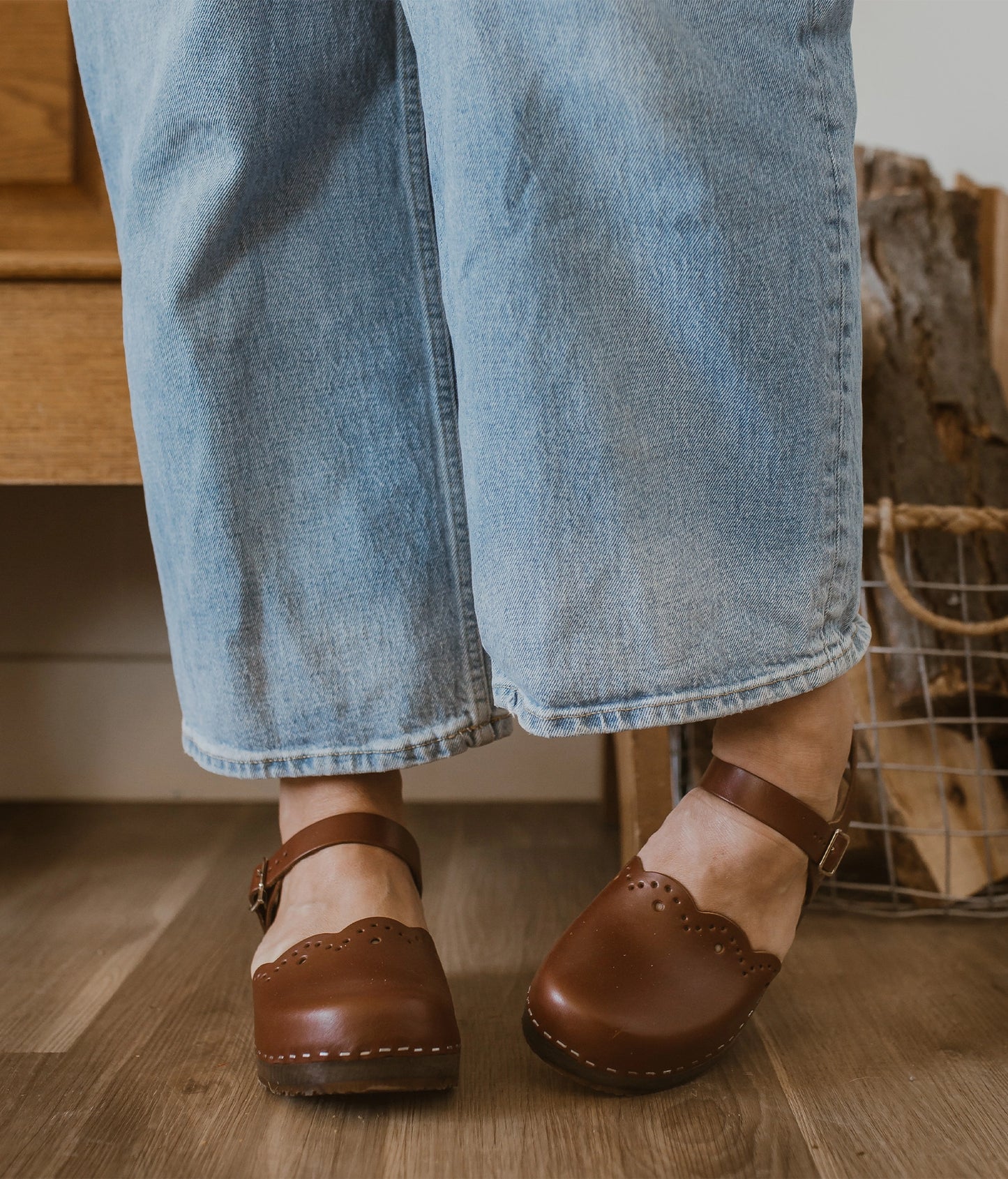 low heeled closed-toe clog sandals in cognac red vegetable tanned leather with a wavy leather cutout stapled on a dark wooden base