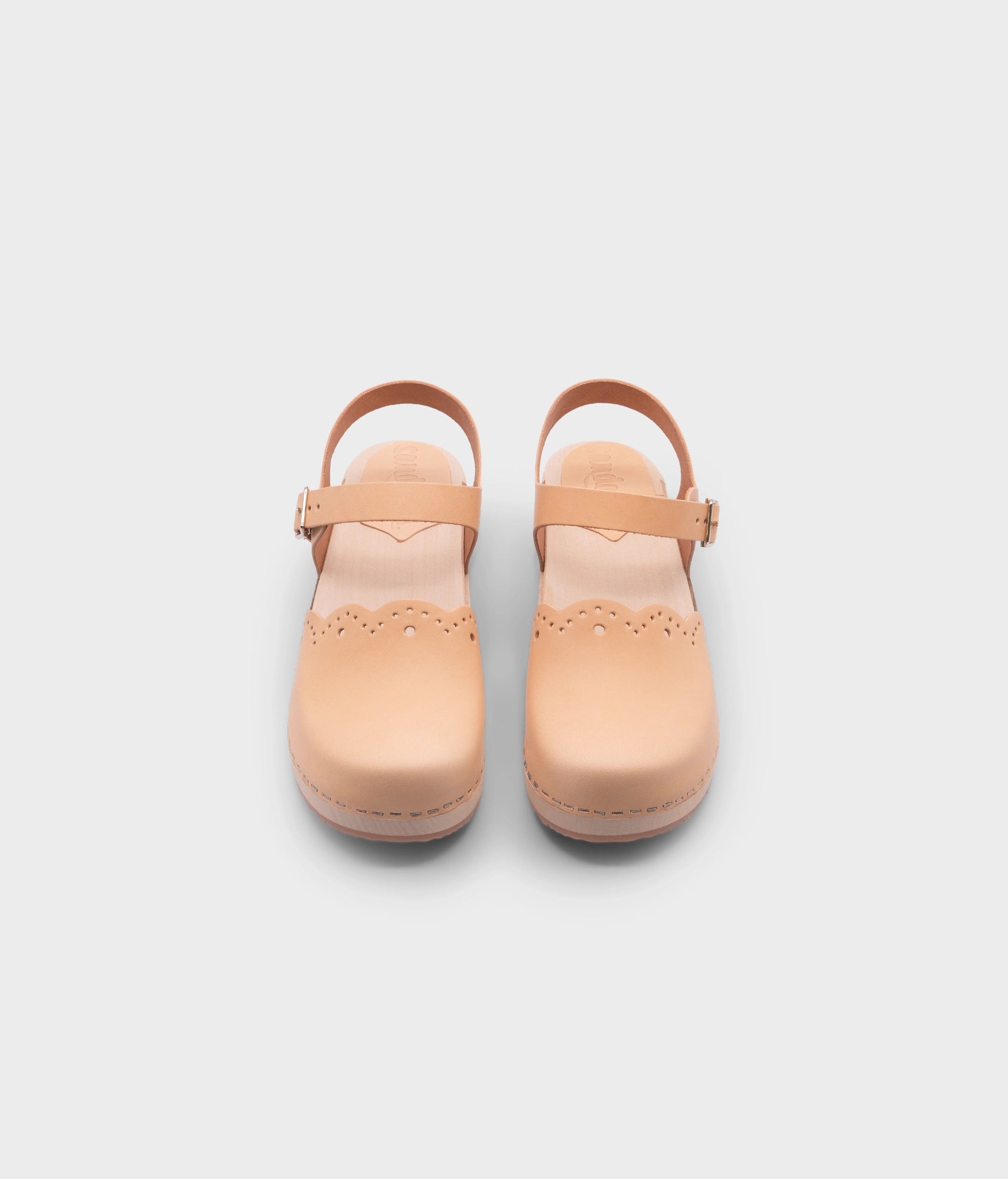 low heeled closed-toe clog sandals in ecru beige vegetable tanned leather with a wavy leather cutout stapled on a light wooden base