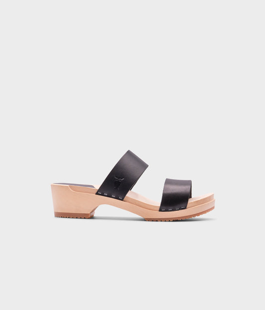 low heeled slip-in clog sandal with open toe in black vegetable tanned leather stapled on a light wooden base