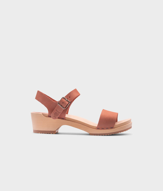 low heeled open-toe clog sandal in blush pink nubuck leather stapled on a light wooden base