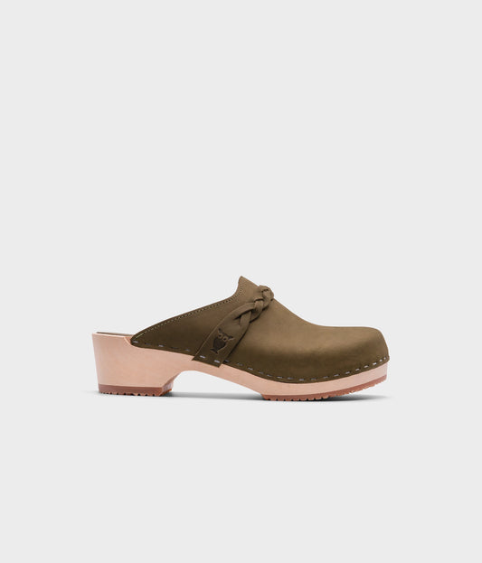 low heeled clog mules in olive green nubuck leather with a braided strap stapled on a light wooden base
