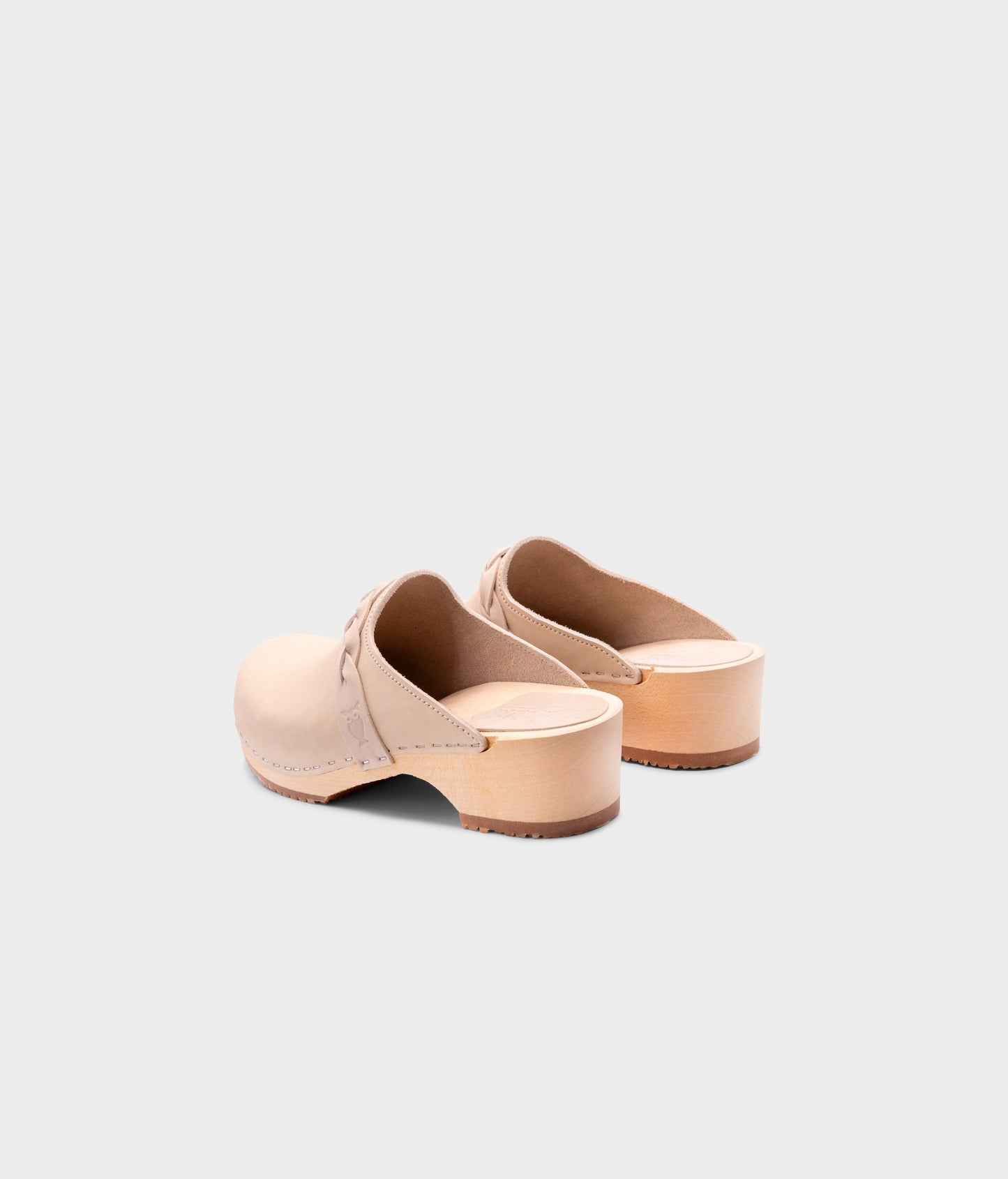 low heeled clog mules in sand white nubuck leather with a braided strap stapled on a light wooden base