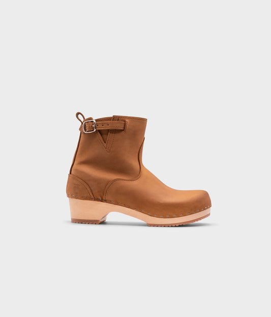 low-heeled clog boots in light brown leather stapled on a light wooden base