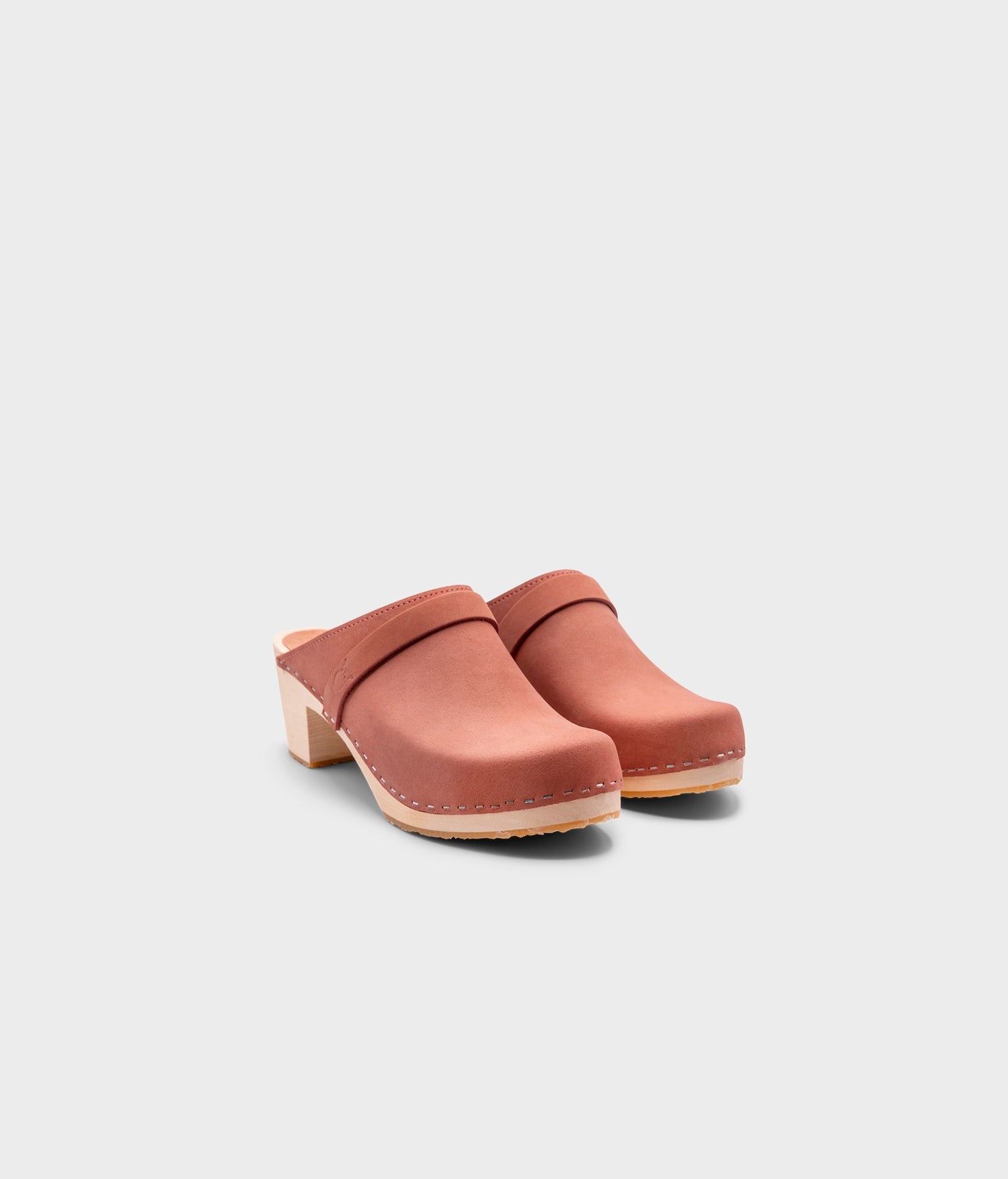 classic high heeled clog mule in blush pink nubuck leather stapled on a light wooden base with a leather strap