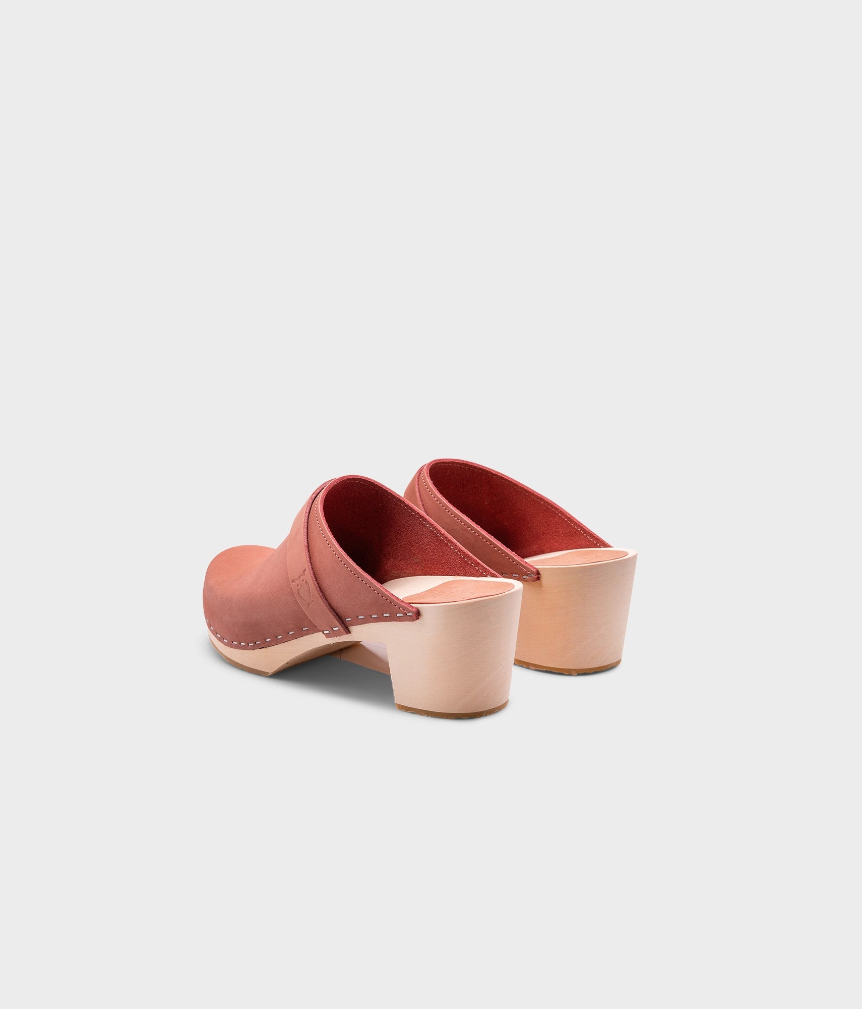 classic high heeled clog mule in blush pink nubuck leather stapled on a light wooden base with a leather strap