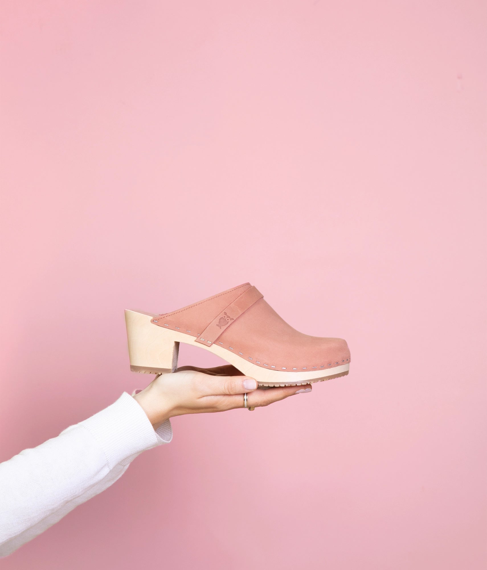 classic high heeled clog mule in blush pink nubuck leather stapled on a light wooden base with a leather strap