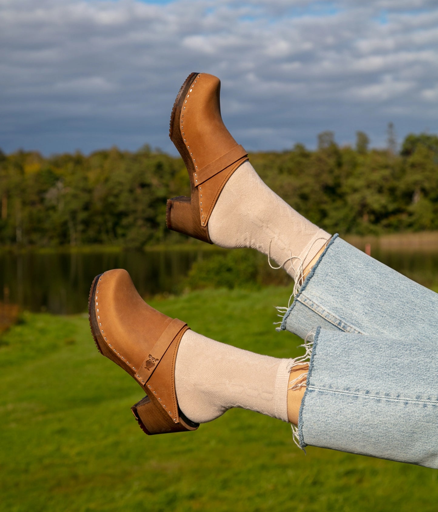 classic high heeled clog mule in light brown nubuck leather stapled on a dark wooden base with a leather strap