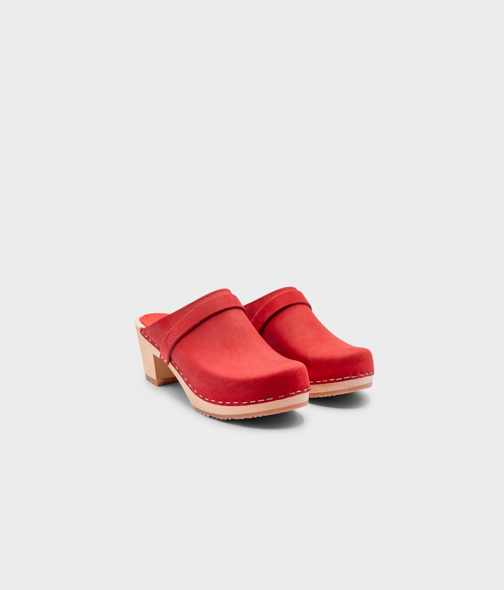 classic high heeled clog mule in red nubuck leather stapled on a light wooden base with a leather strap