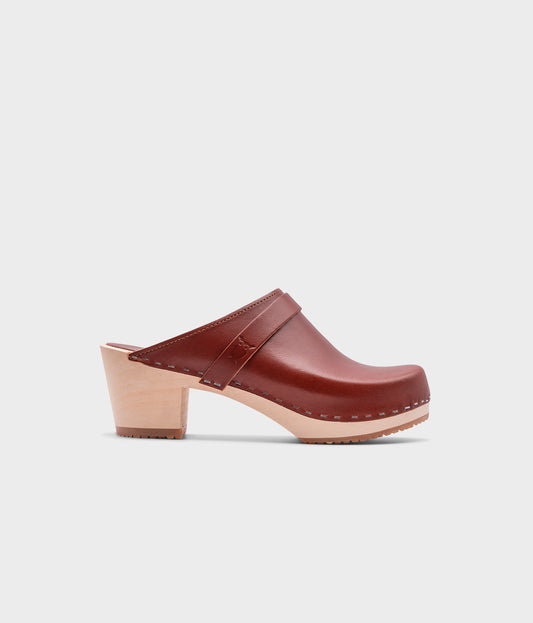 classic high heeled clog mule in cognac red vegetable tanned leather stapled on a light wooden base with a leather strap