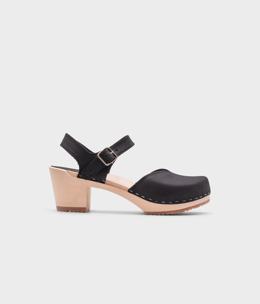 high heeled closed-toe clog sandal in black nubuck leather stapled on a light wooden base