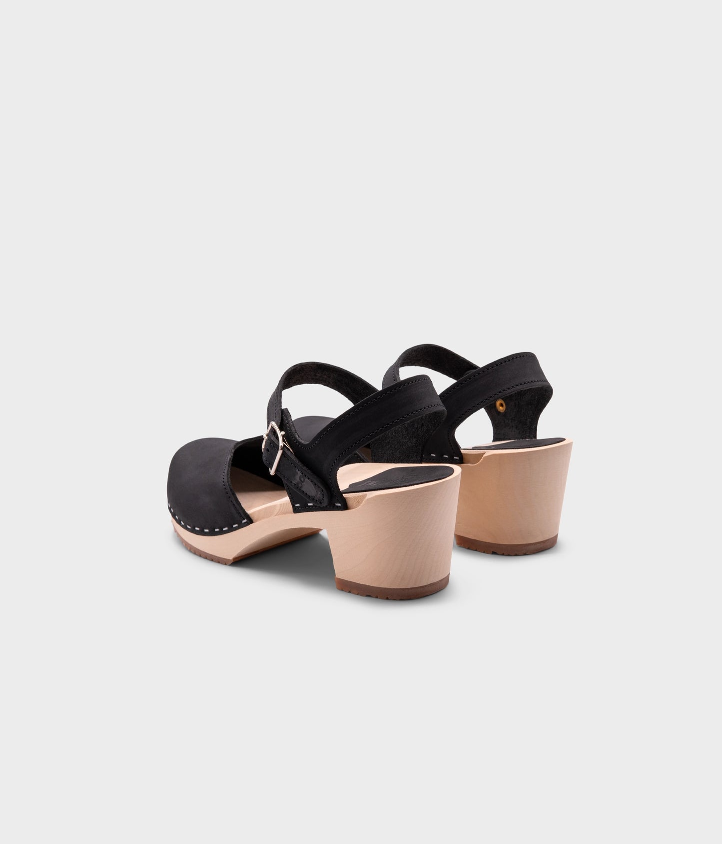 high heeled closed-toe clog sandal in black nubuck leather stapled on a light wooden base