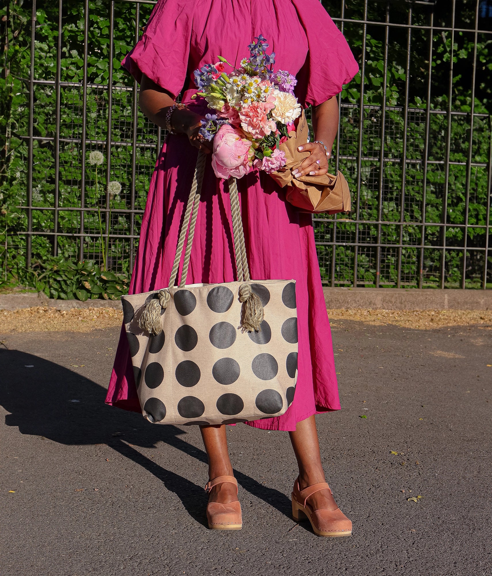 woman wearing a pink dress and a pair of high heeled closed-toe clog sandal in blush pink nubuck leather stapled on a light wooden base