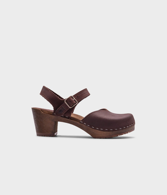 high heeled closed-toe clog sandal in dark brown nubuck leather stapled on a dark wooden base