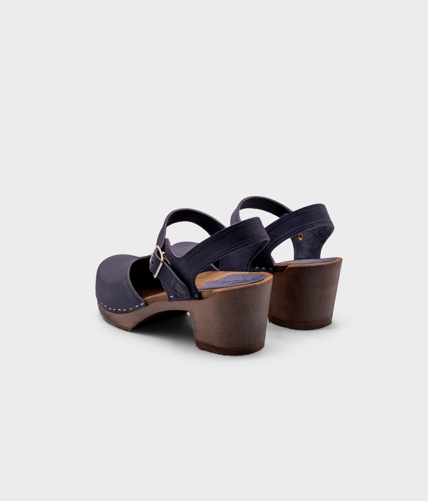 high heeled closed-toe clog sandal in navy blue nubuck leather stapled on a dark wooden base