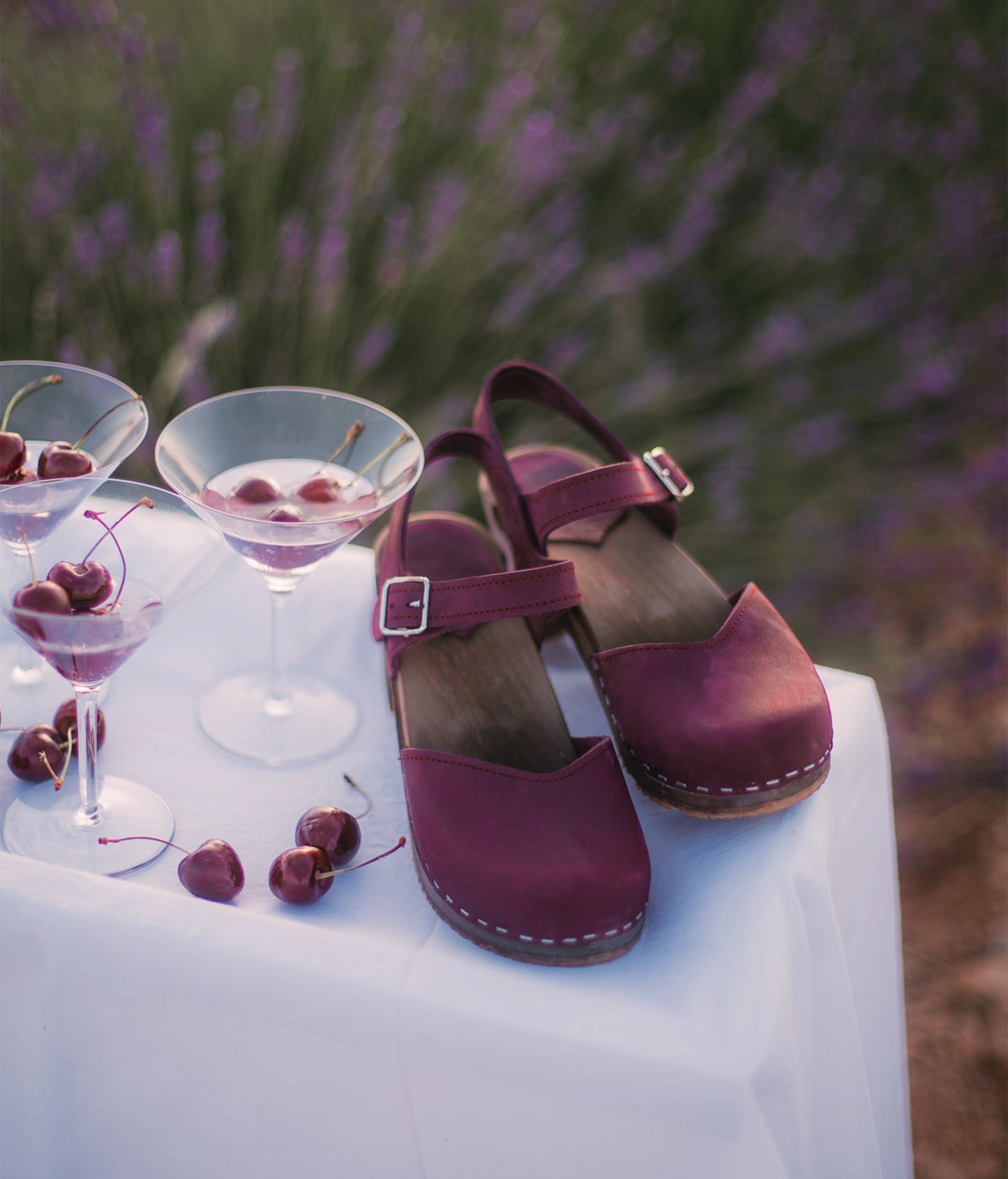 high heeled closed-toe clog sandal in purple plum nubuck leather stapled on a dark wooden base