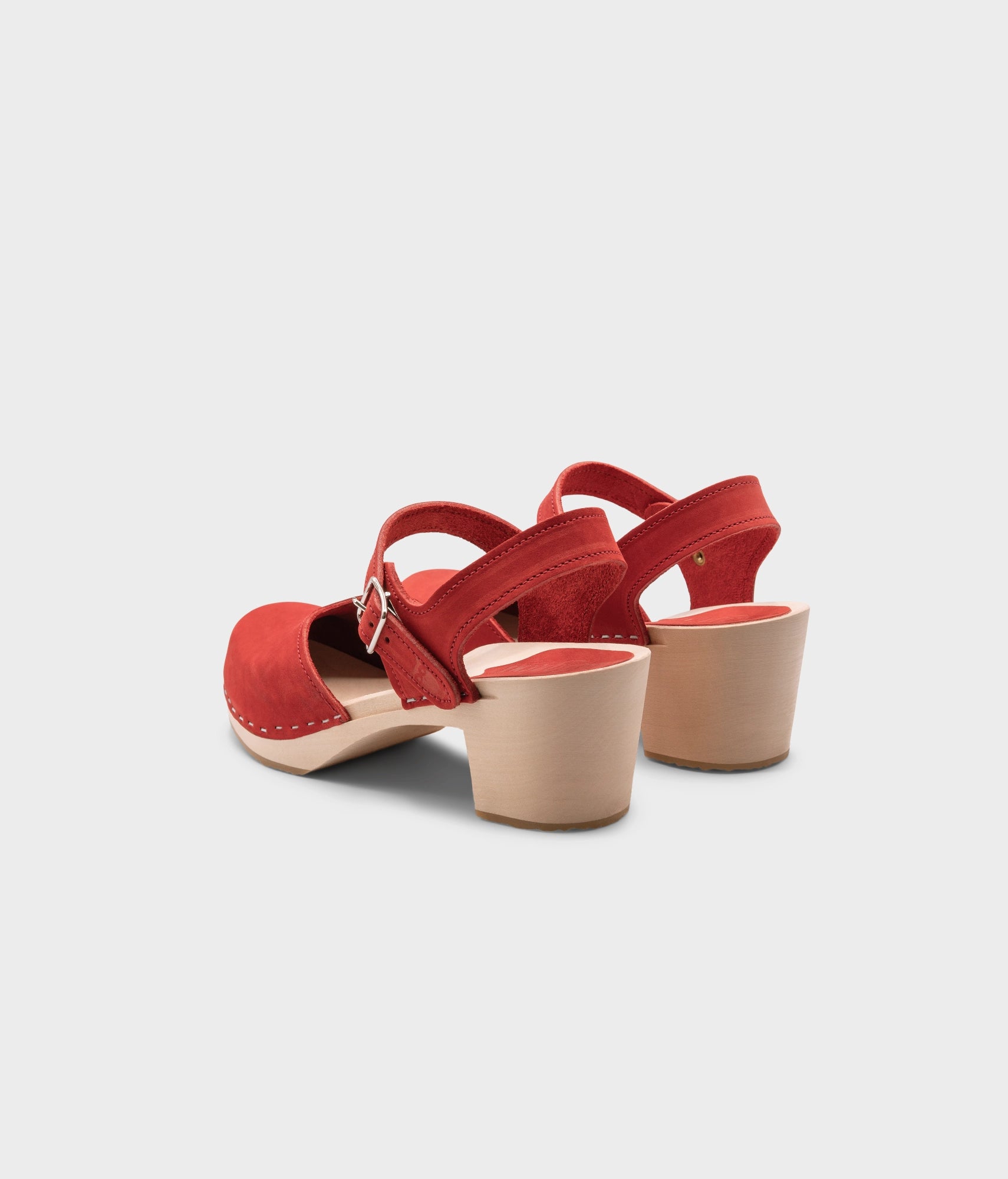 high heeled closed-toe clog sandal in red nubuck leather stapled on a light wooden base