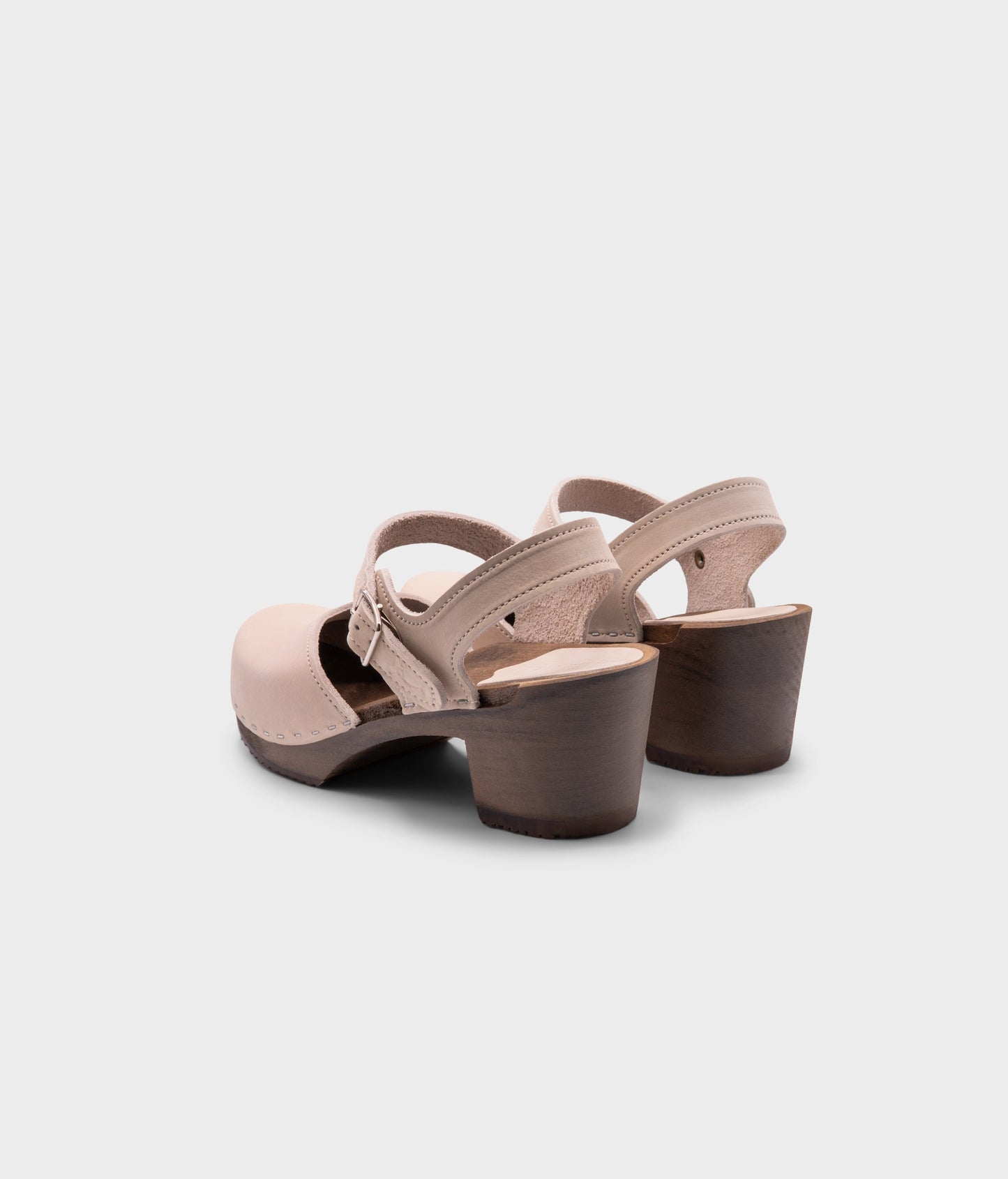 high heeled closed-toe clog sandal in sand white nubuck leather stapled on a dark wooden base