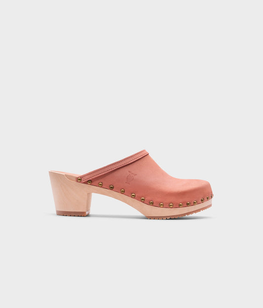 high heeled clog mules in blush pink nubuck leather stapled on a light wooden base with brass gold studs