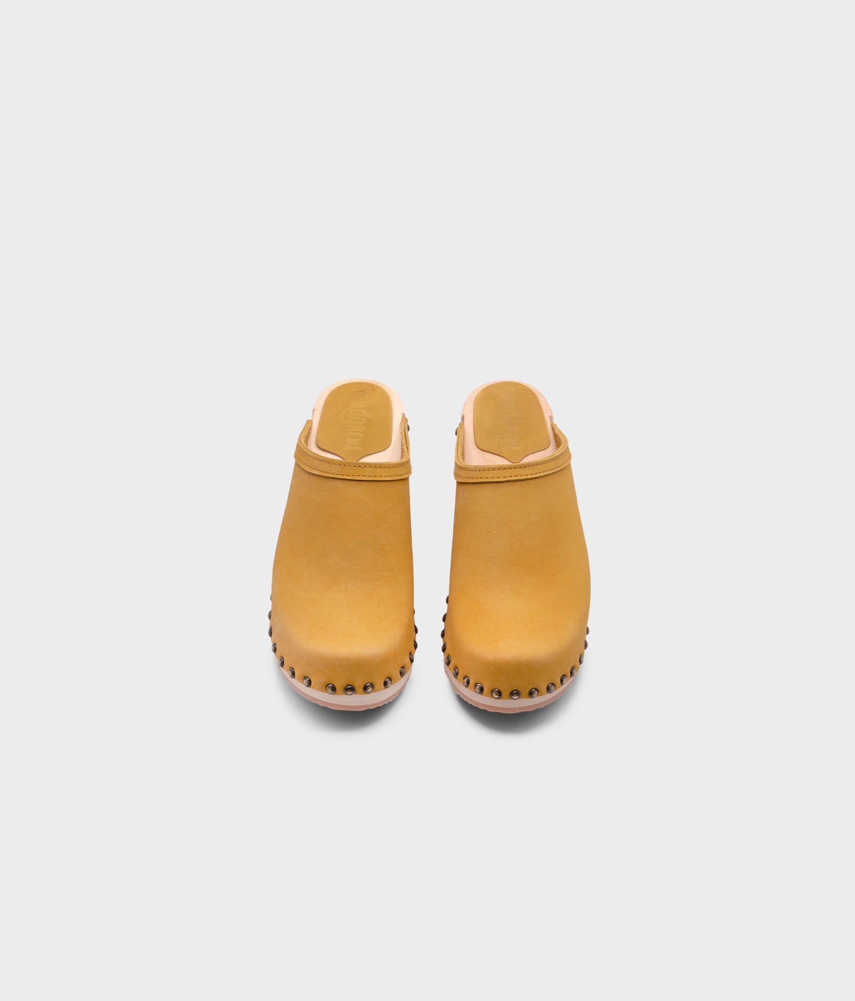 high heeled clog mules in yellow nubuck leather stapled on a light wooden base with brass gold studs