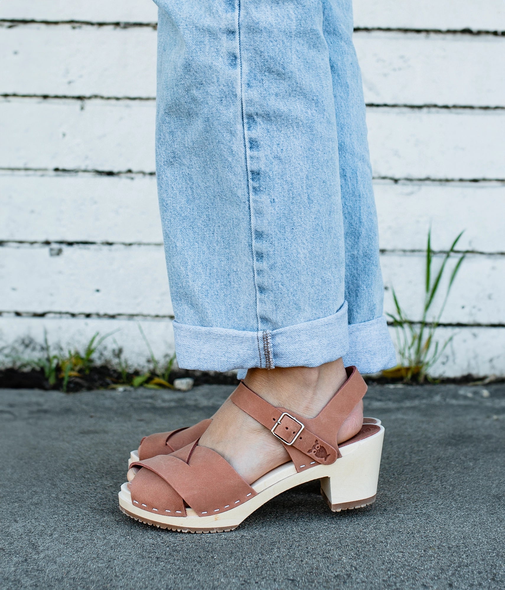 high heeled clog sandals in blush pink nubuck leather with an open-toe stapled on a light wooden base