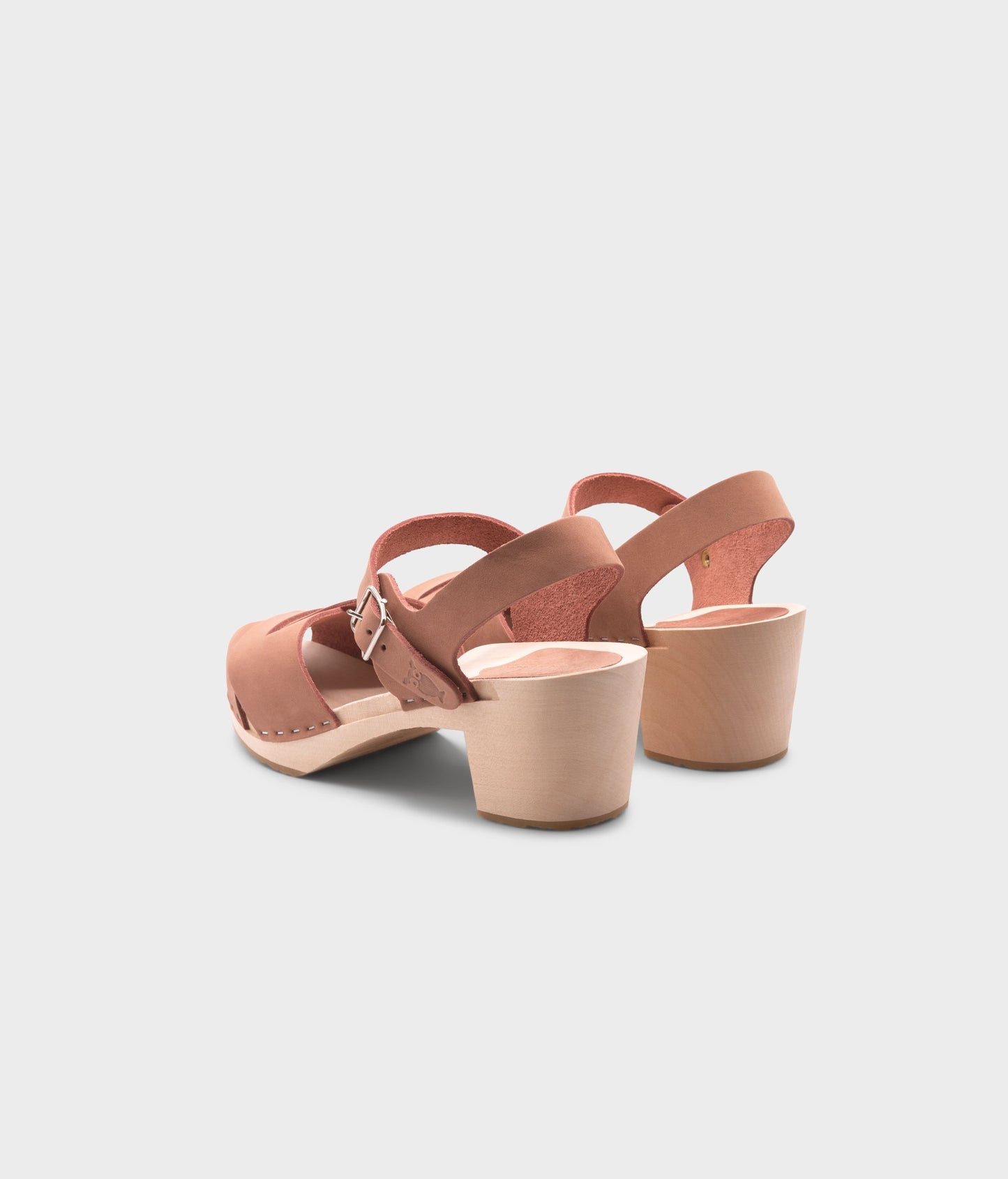 high heeled clog sandals in blush pink nubuck leather with an open-toe stapled on a light wooden base