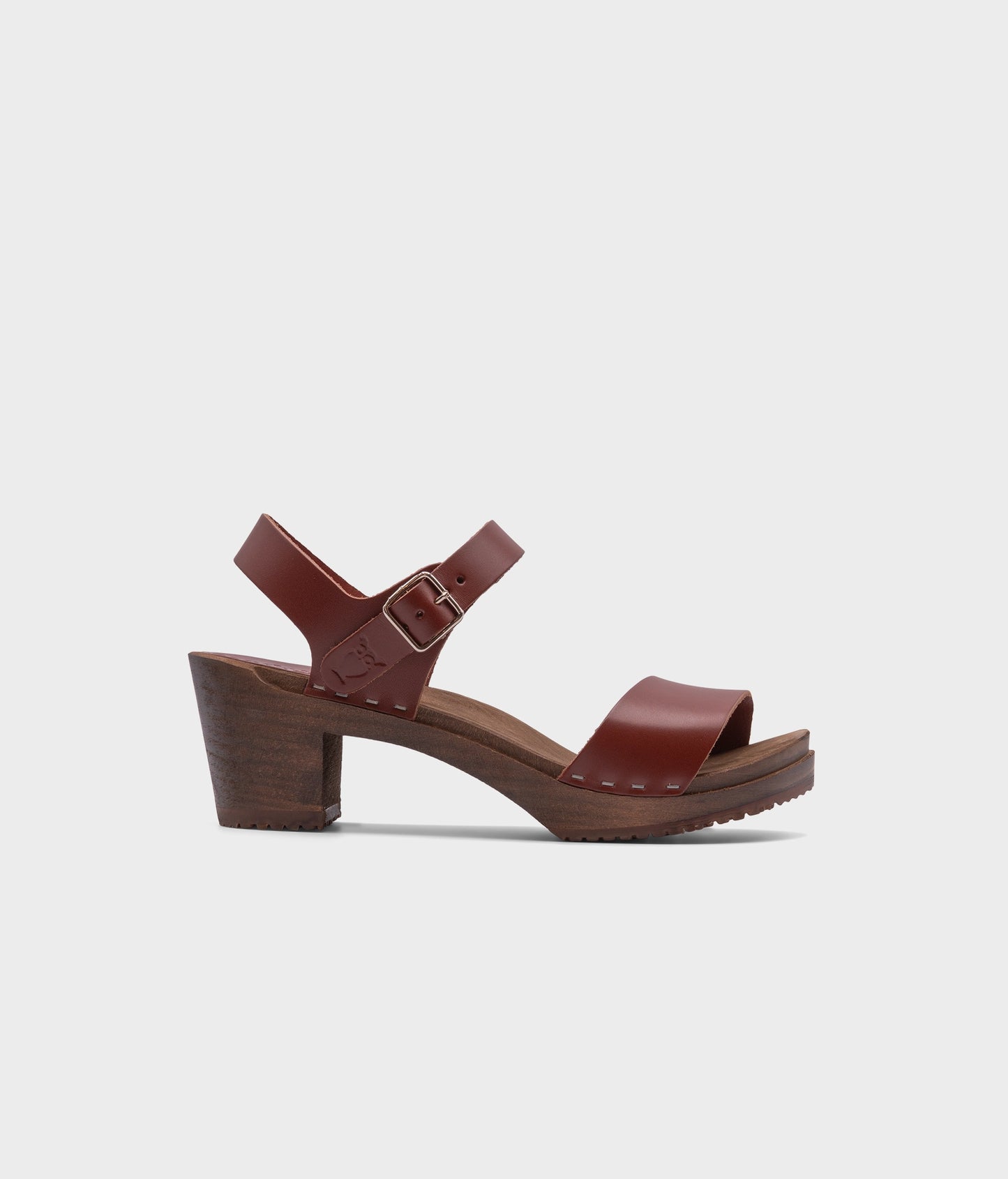 high-heeled open-toe clog sandal in cognac red vegetable tanned leather stapled on a dark wooden base