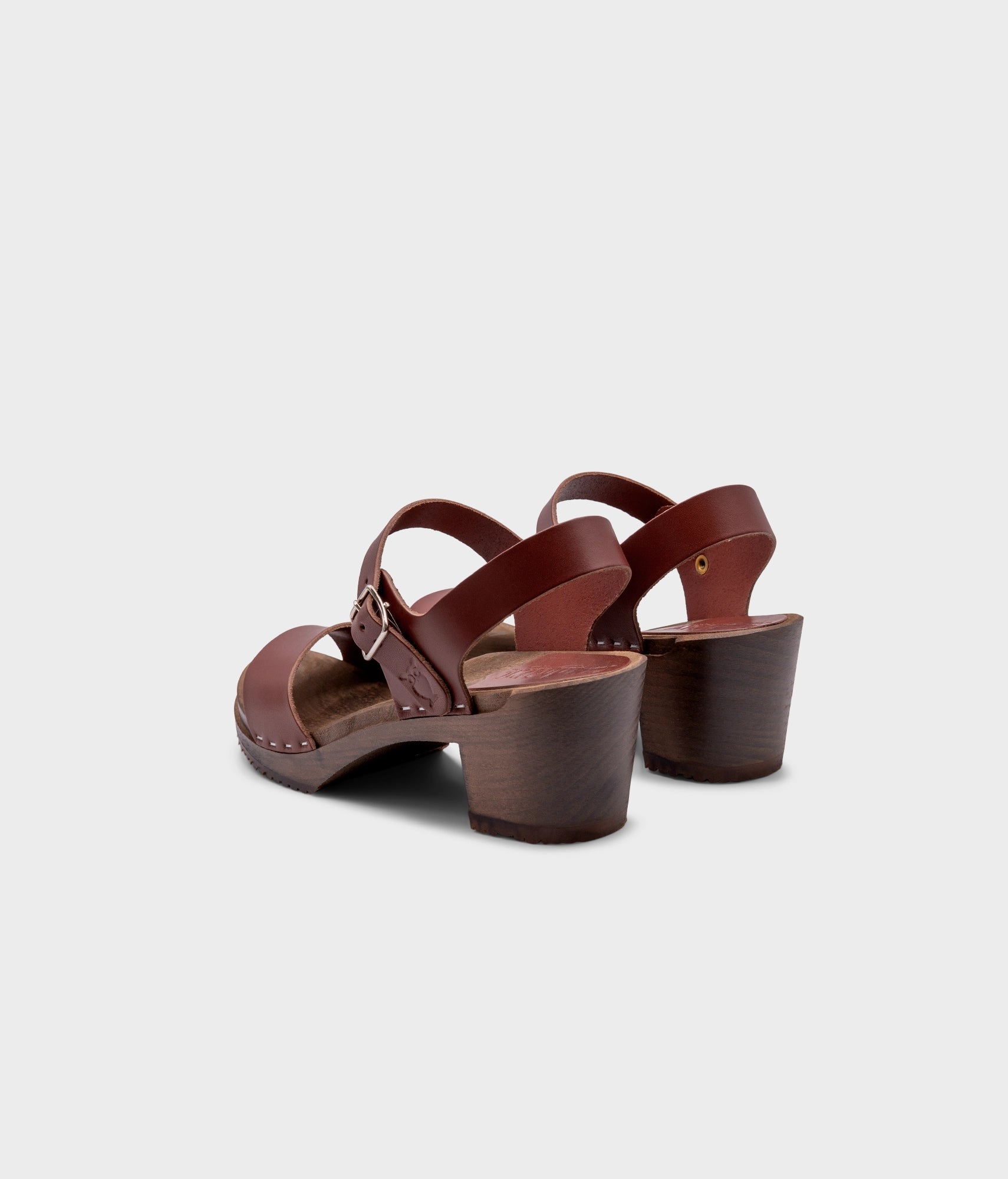 high-heeled open-toe clog sandal in cognac red vegetable tanned leather stapled on a dark wooden base