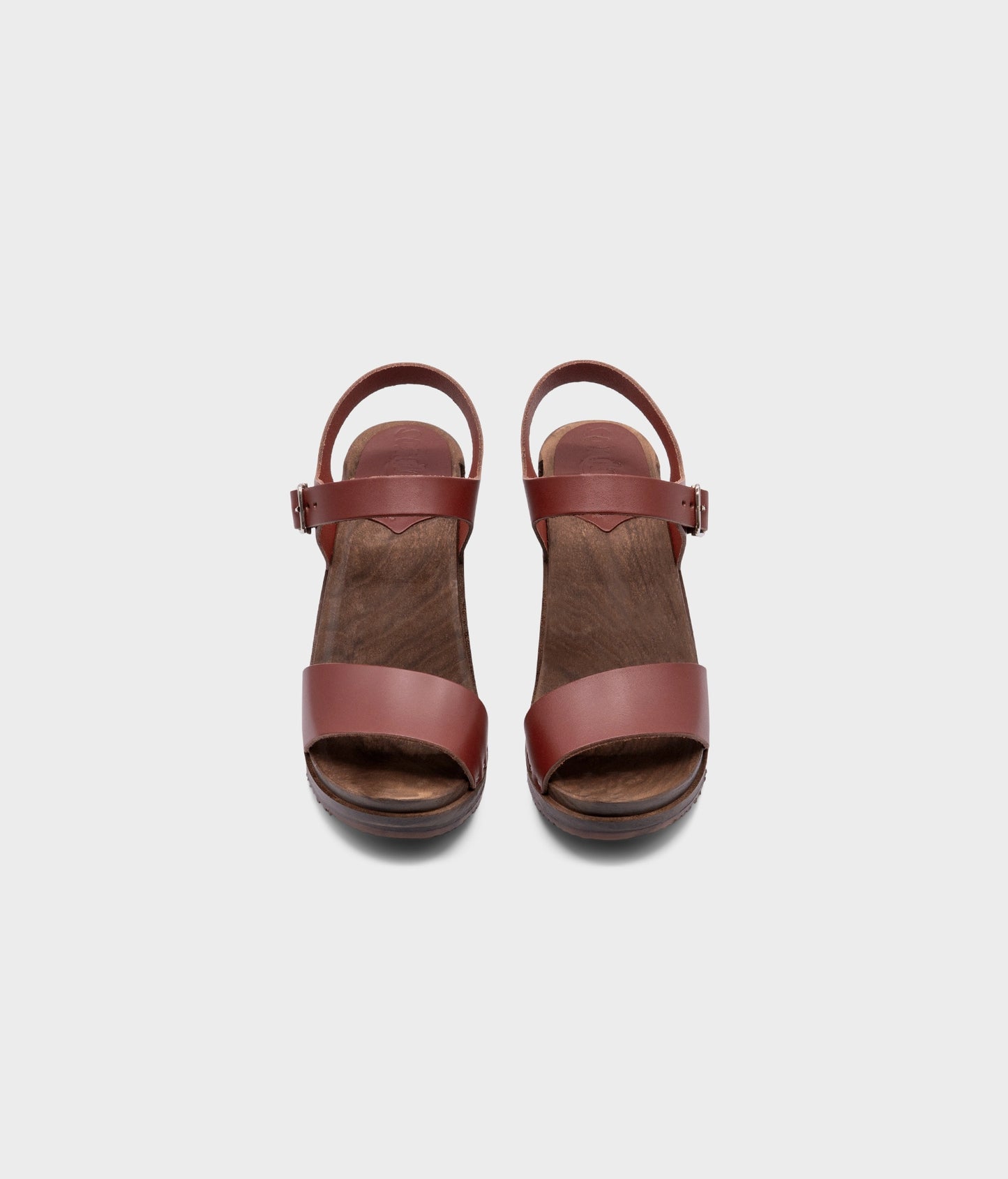 high-heeled open-toe clog sandal in cognac red vegetable tanned leather stapled on a dark wooden base