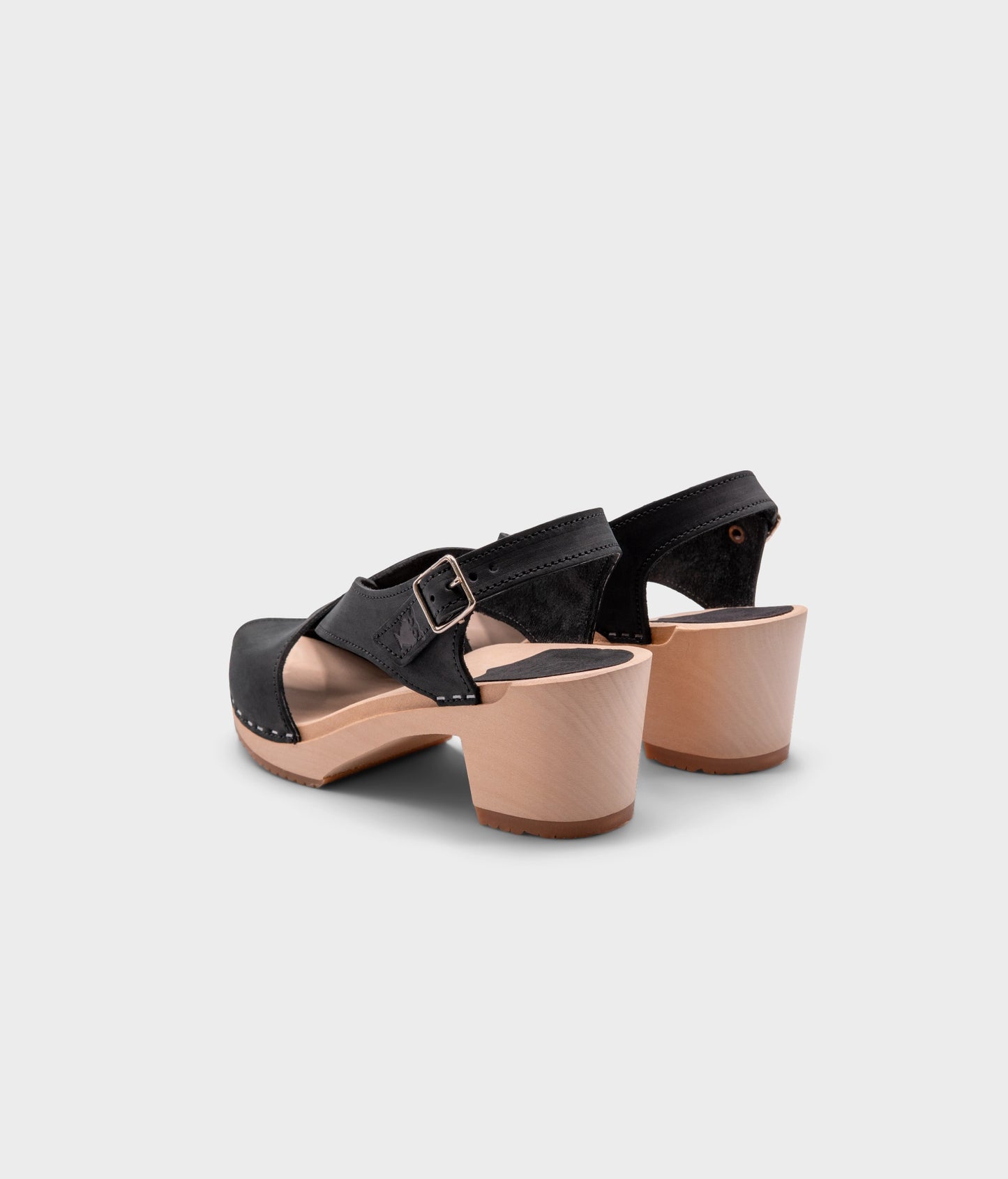 high heeled criss cross clog sandals in black nubuck leather stapled on a light wooden base