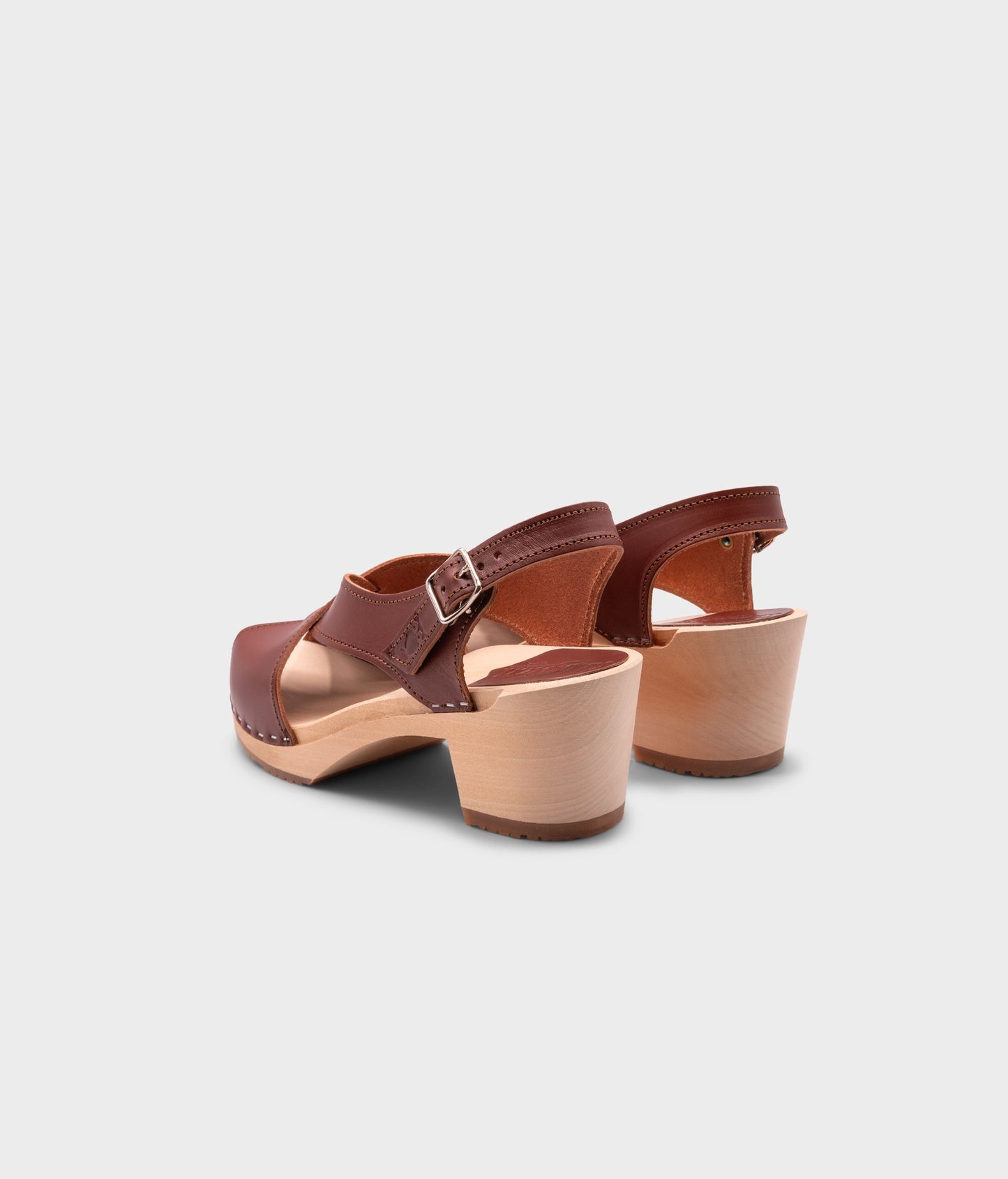 high heeled criss cross clog sandals in cognac red vegetable tanned leather stapled on a light wooden base