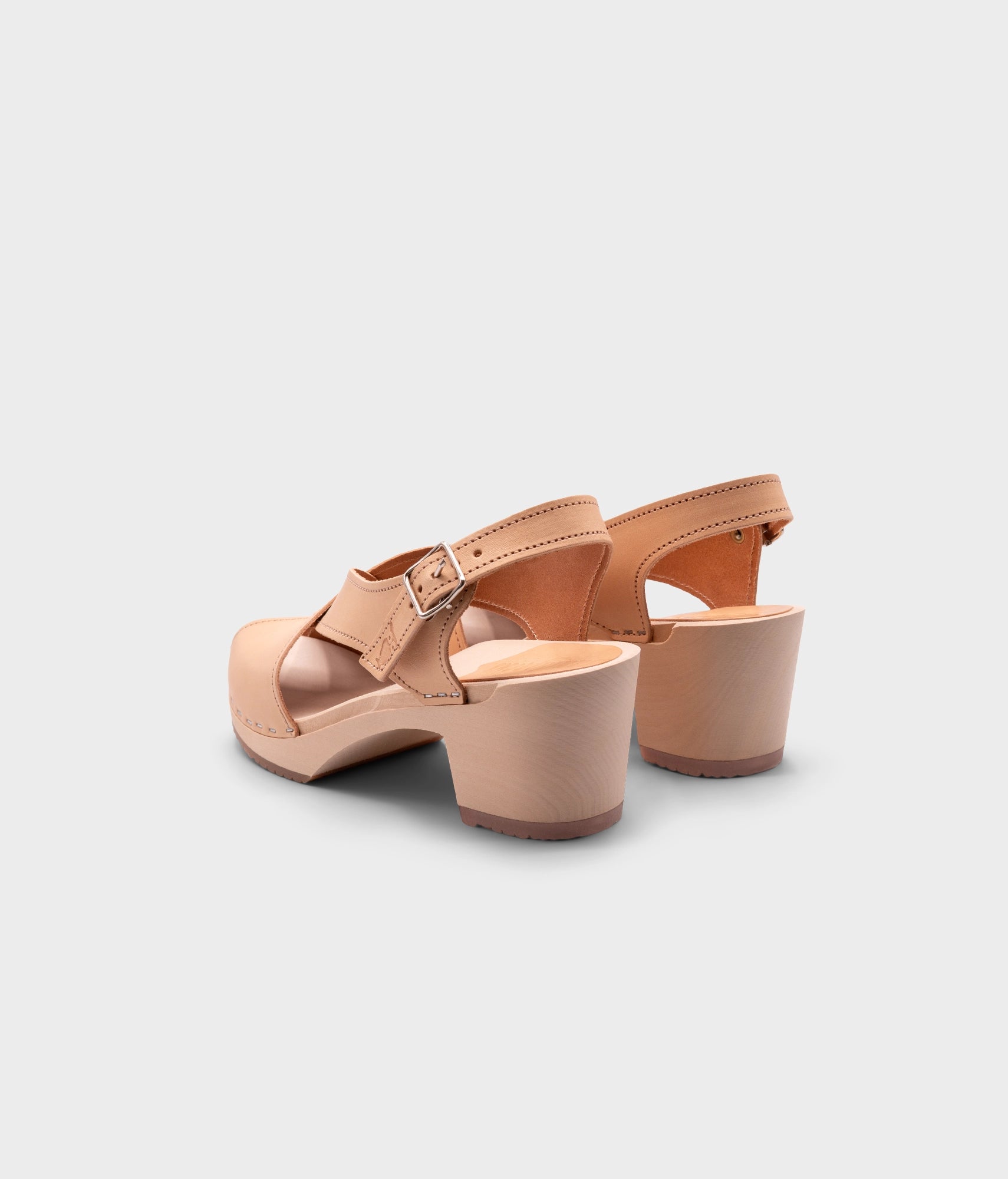high heeled criss cross clog sandals in ecru beige vegetable tanned leather stapled on a light wooden base