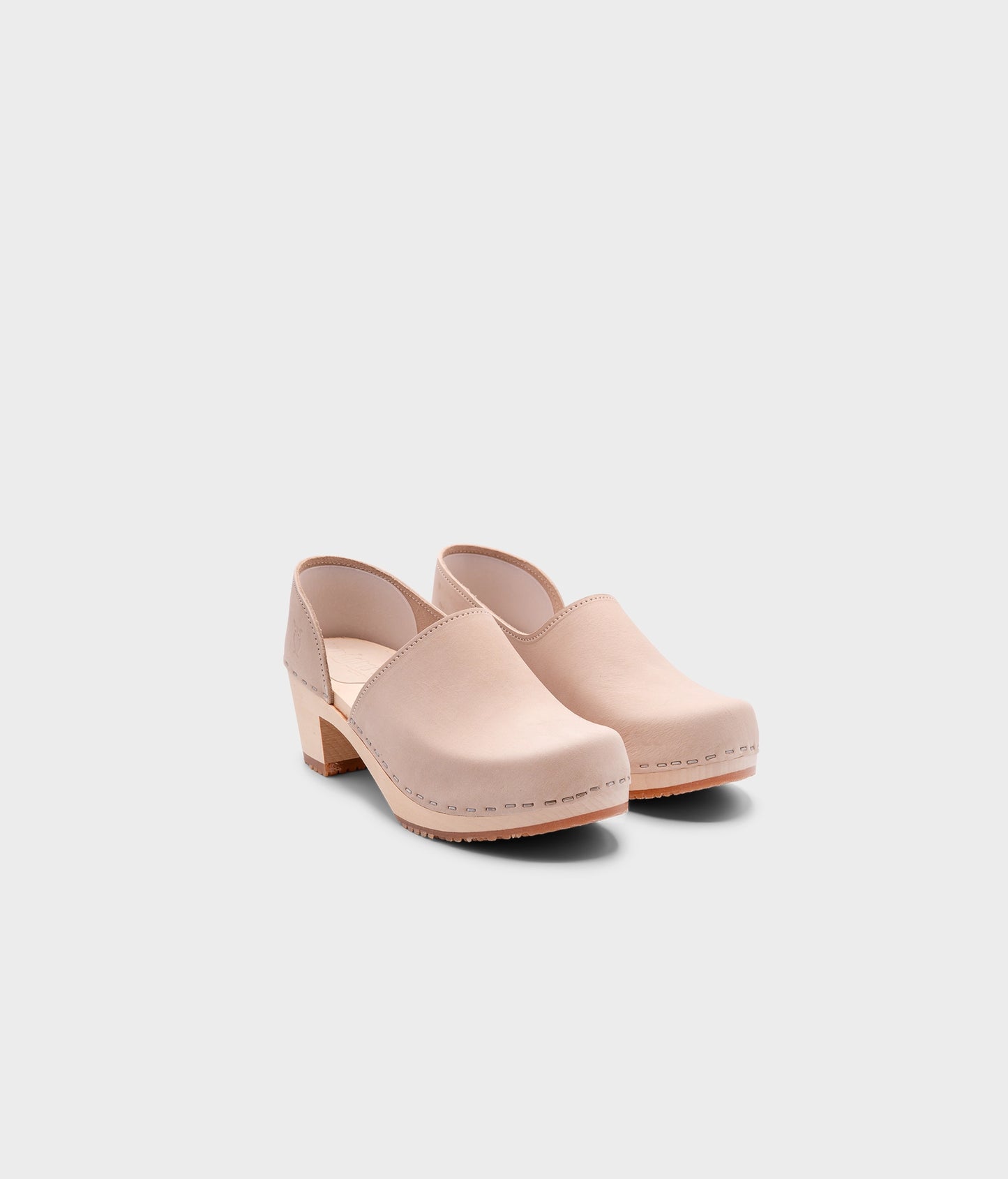 high heeled closed-back clogs in sand white nubuck leather stapled on a light wooden base