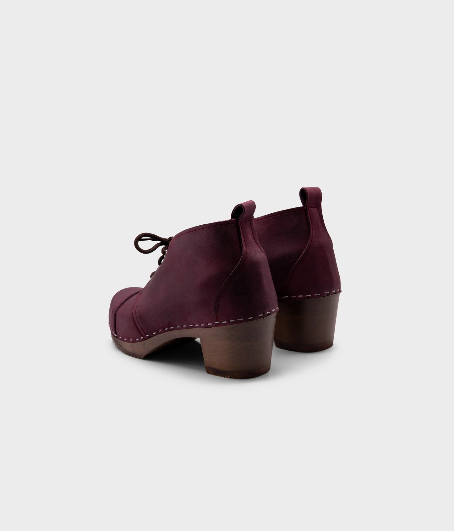 high heeled chukka clog boots in purple plum nubuck leather stapled on a dark wooden base with brown laces