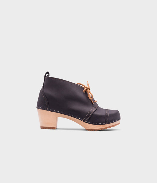 high heeled chukka clog boots in navy blue nubuck leather stapled on a light wooden base with beige laces
