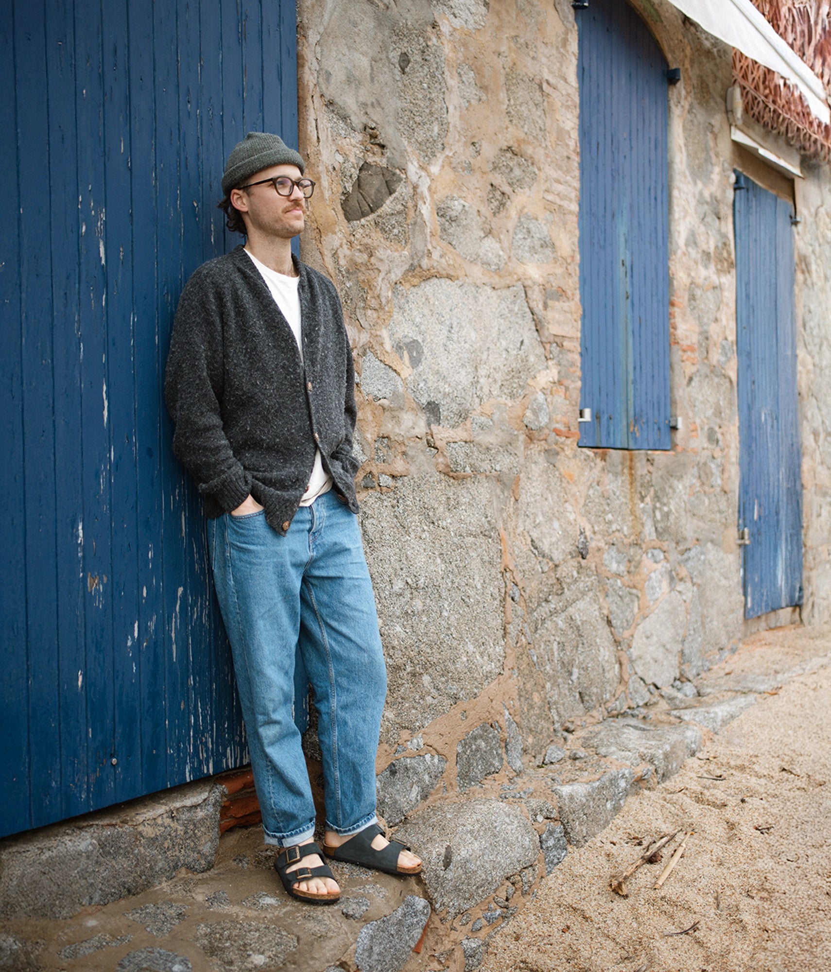 Man leaning against a stone wall with blue cork sandals